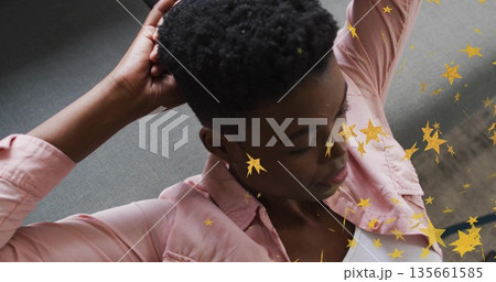 Reclining woman placing hands behind head at home on grey upholstered sofa, with star overlay 135661585