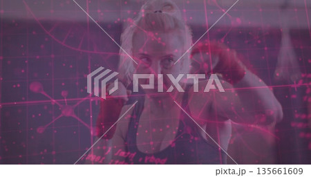 Practicing boxer throwing punches inside gym with punching bag and red wraps, digital grid overlay 135661609