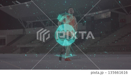 Dribbling athlete in orange jersey on field under floodlights, holographic ball emitting particles Dribbling athlete in orange jersey on field under floodlights, holographic ball emitting particles 135661616