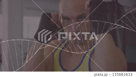 Holding fists up boxer wearing yellow tank top, wraps in gym, with punching bag, DNA overlay Holding fists up boxer wearing yellow tank top, wraps in gym, with punching bag, DNA overlay 135661633