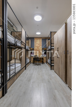 Symmetrical vertical shot of a loft hostel dormitory with bunk beds and wooden lockers 135663801