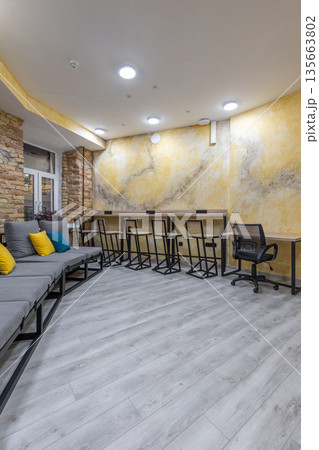 Spacious hostel common area with modular sofa, bar counter, and coworking space 135663802