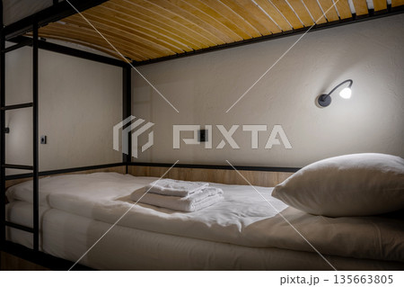 Close-up of a neat bunk bed in a loft hostel with warm lighting 135663805