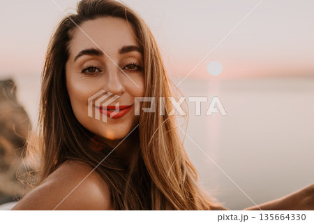Woman sunset beach smiling female traveler enjoys golden hour by the ocean during a summer vacation 135664330