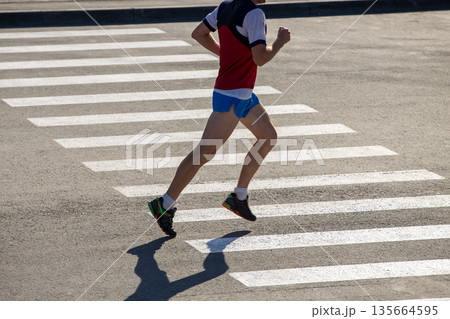 Male athlete running race on road 135664595