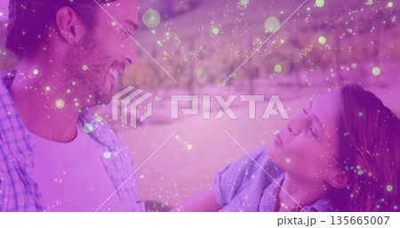 Smiling couple leaning toward each other in park orchard, with sparkly bokeh light overlay Smiling couple leaning toward each other in park orchard, with sparkly bokeh light overlay 135665007