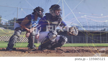 Crouching catchers holding mitts at baseball home plate, with helmets and chest protectors 135665121