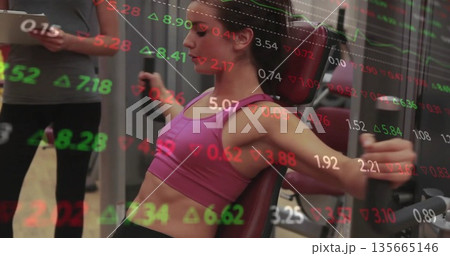 Pushing chest press grips woman in sportswear in gym with tablet-holding trainer and ticker overlay Pushing chest press grips woman in sportswear in gym with tablet-holding trainer and ticker overlay 135665146