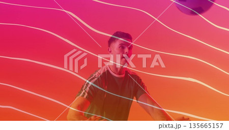 Pedaling male enthusiast wearing green sports shirt on stationary bike in studio, with neon streaks Pedaling male enthusiast wearing green sports shirt on stationary bike in studio, with neon streaks 135665157