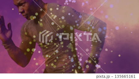 Male athlete lunging in studio, wearing gray compression top amid purple-orange gradient particles Male athlete lunging in studio, wearing gray compression top amid purple-orange gradient particles 135665161