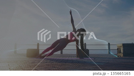 Woman holding side plank pose in sportswear on stone pier at sunrise, with mat, block, railing Woman holding side plank pose in sportswear on stone pier at sunrise, with mat, block, railing 135665165