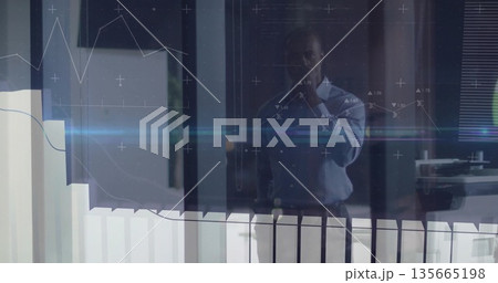 Analyzing data display businessman standing behind glass partition in corporate office, with graphs 135665198