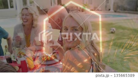 Smiling mid adult woman in summer dress sipping drink at backyard patio table, with salad bowl 135665389