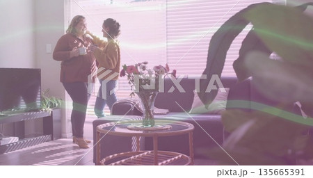 Chatting friends holding white mugs and adjusting hair in living room with coffee table, copy space Chatting friends holding white mugs and adjusting hair in living room with coffee table, copy space 135665391