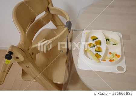 木製ハイチェアと手づかみ食べ用の離乳食の野菜が置かれたテーブル 木製ハイチェアと手づかみ食べ用の離乳食の野菜が置かれたテーブル 135665655