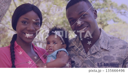 Smiling parents holding baby in park, with uniform, blouse, romper and headband star overlays 135666496