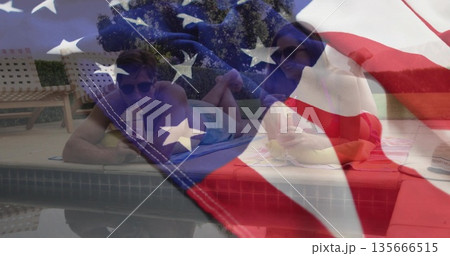 Basking couple wearing swimwear lying on towels at home poolside, with plastic cup flag overlay Basking couple wearing swimwear lying on towels at home poolside, with plastic cup flag overlay 135666515