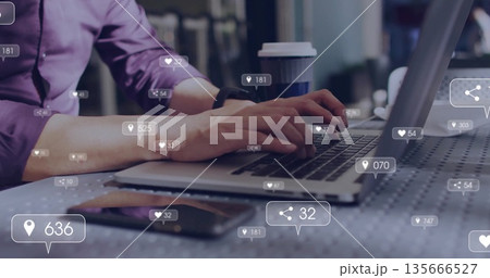 Asian man wearing purple shirt typing on laptop in cafe, with smartphone coffee cup, floating icons 135666527
