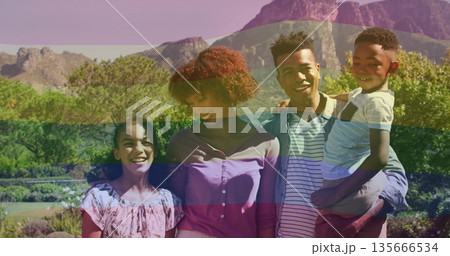 Standing family of four in spring outfits in landscaped garden, with flowering shrubs and mountains Standing family of four in spring outfits in landscaped garden, with flowering shrubs and mountains 135666534