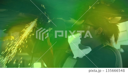 Grinding mechanic using angle grinder under chassis in shop with gloves, safety glasses, copy space Grinding mechanic using angle grinder under chassis in shop with gloves, safety glasses, copy space 135666548