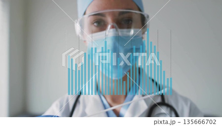 Displaying physician wearing labcoat and mask with stethoscope viewing digital bar chart in clinic Displaying physician wearing labcoat and mask with stethoscope viewing digital bar chart in clinic 135666702