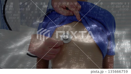 Senior doctor placing stethoscope on boys chest lifting blue T-shirt at exam table and binary code 135666759