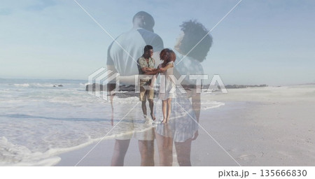 Walking barefoot couple holding hands at beach water's edge, showing double exposure overlay 135666830