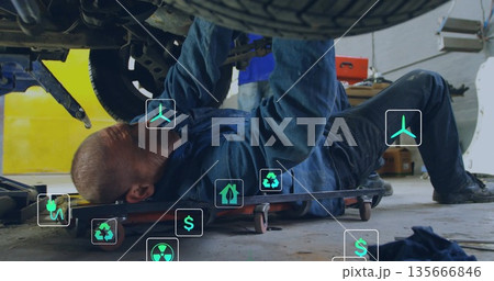 Inspecting mechanic in coveralls examining undercarriage on creeper in garage, with red tool chest Inspecting mechanic in coveralls examining undercarriage on creeper in garage, with red tool chest 135666846