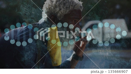 Holding mouthpiece to lips, African American man leaning by window, with yellow towel and DNA helix 135666907