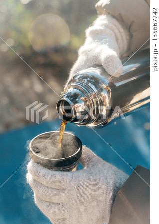 Coffee Pouring from Thermos into Cup on a Sunny Winter Day Coffee Pouring from Thermos into Cup on a Sunny Winter Day 135667242