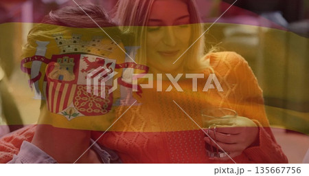 Sitting couple sharing moment in home living room, with clear glass mug and Spanish flag overlay Sitting couple sharing moment in home living room, with clear glass mug and Spanish flag overlay 135667756