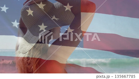 Standing adult woman wearing straw hat and red swimsuit at water's edge, with American flag overlay Standing adult woman wearing straw hat and red swimsuit at water's edge, with American flag overlay 135667785