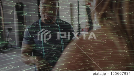 Measuring male trainer gauging client body dimensions with tape near punching bag in gym 135667954