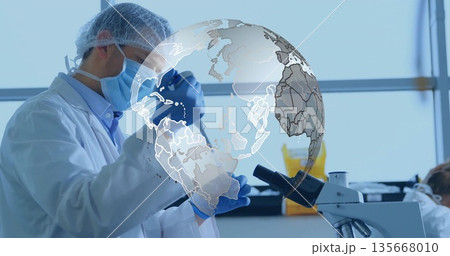 Researcher in lab gear pipetting in lab with test tube, biohazard bin, digital globe graphic 135668010