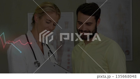 White-coated physician and patient examining clipboard in exam room, with stethoscope and charts 135668048