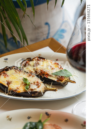 Baked eggplant halves with melted cheese 135668271