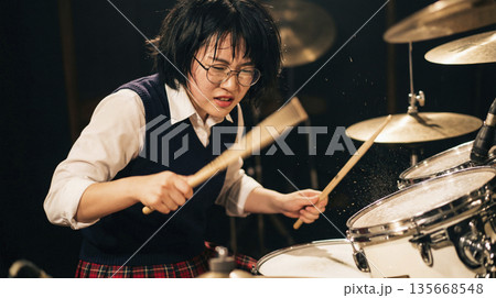 ライブハウスで汗を流して激しくドラムを叩く眼鏡をかけた女子高生 135668548