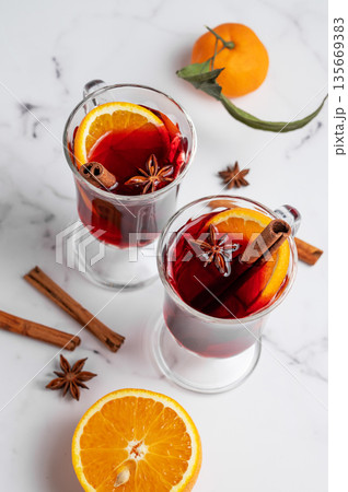 Two glasses of mulled wine, orange, cinnamon, and star anise on a marble background with spice 135669383
