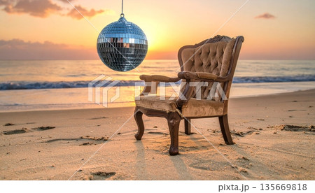 A wooden bench and a beach chair sit on the sand facing the ocean waves under a vibrant sunset sky 135669818