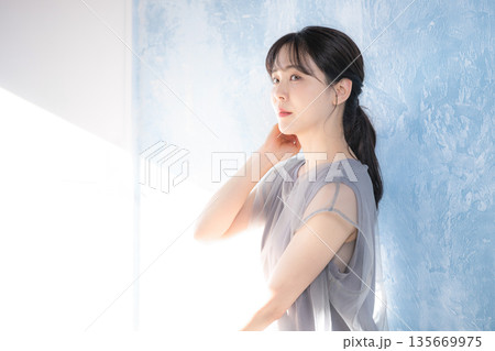 水色背景で日射しの中でポーズをとる女性の横顔 上半身 eラインのイメージ 水色背景で日射しの中でポーズをとる女性の横顔 上半身 eラインのイメージ 135669975