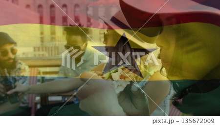 Gathering four friends sitting around table on rooftop deck, holding tacos with Ghana flag overlay 135672009