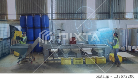 Technician loading yellow crates onto conveyor in processing hall, supervisor consulting tablet Technician loading yellow crates onto conveyor in processing hall, supervisor consulting tablet 135672200