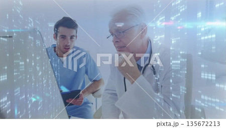 Analyzing doctors in lab coat and scrubs reviewing patient data at hospital with monitor and tablet 135672213