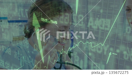 Doctor in scrubs listening with stethoscope at monitors in clinic, colleague viewing green charts 135672275