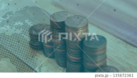 Rising copper coin stacks occupying wooden office desk, featuring dotted world map overlay 135672361