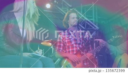Playing electric guitar, guitarist wearing red shirt on concert stage with drums and trusses Playing electric guitar, guitarist wearing red shirt on concert stage with drums and trusses 135672399
