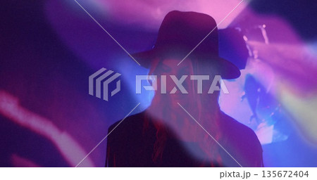 Standing adult woman wearing wide hat performing on nightclub stage, with colorful lights and haze Standing adult woman wearing wide hat performing on nightclub stage, with colorful lights and haze 135672404