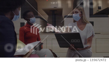 Masked professionals discussing virus overlays in office lounge, holding laptop and smartphone Masked professionals discussing virus overlays in office lounge, holding laptop and smartphone 135672472