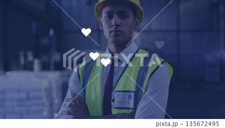 Overseeing site supervisor wearing safety vest, helmet, ID badge inside warehouse, stacked pallets Overseeing site supervisor wearing safety vest, helmet, ID badge inside warehouse, stacked pallets 135672495