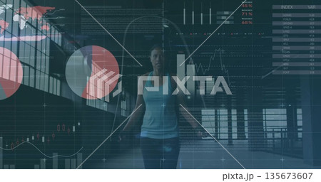 Jumping athletic woman gripping rope in gym studio, with grid windows and financial chart overlay Jumping athletic woman gripping rope in gym studio, with grid windows and financial chart overlay 135673607
